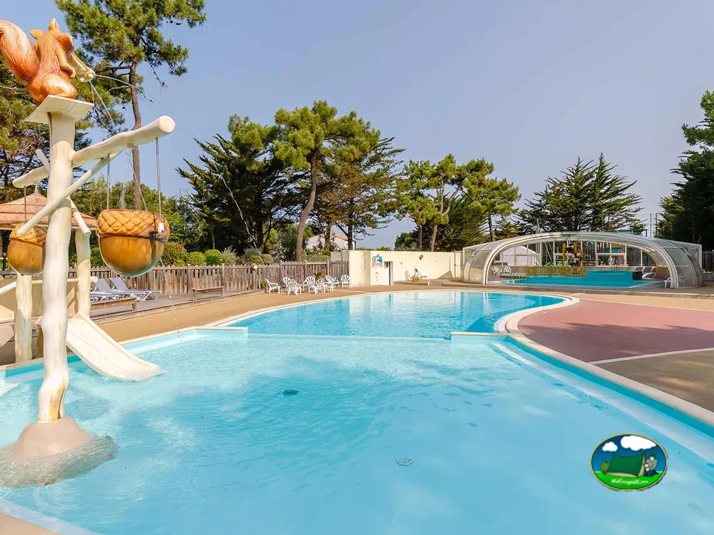 piscina infantil con tobogán temático de ardilla y piscina cubierta al fondo
