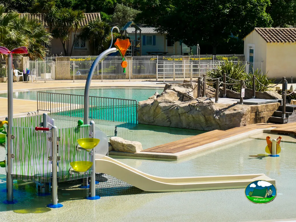 zona de juegos acuáticos con toboganes y piscina infantil junto a rocas artificiales