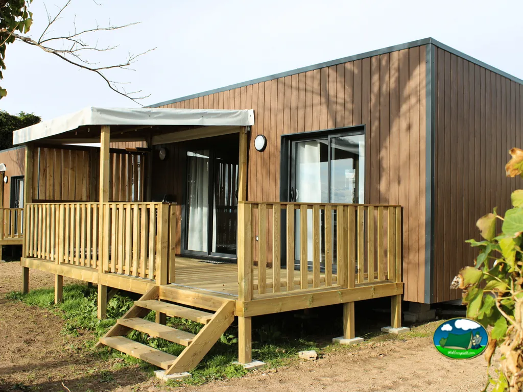 mobile home moderno de madera con terraza y porche cubierto en el camping