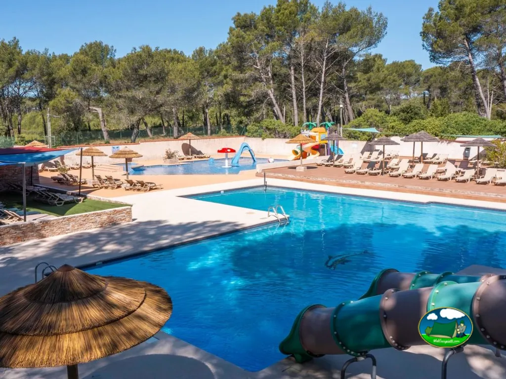 piscina con toboganes y zona infantil rodeada de tumbonas en Castellet