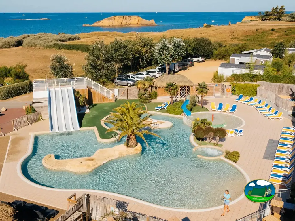 vista aérea de la piscina con tobogán junto al mar y las parcelas del camping en Pénestin