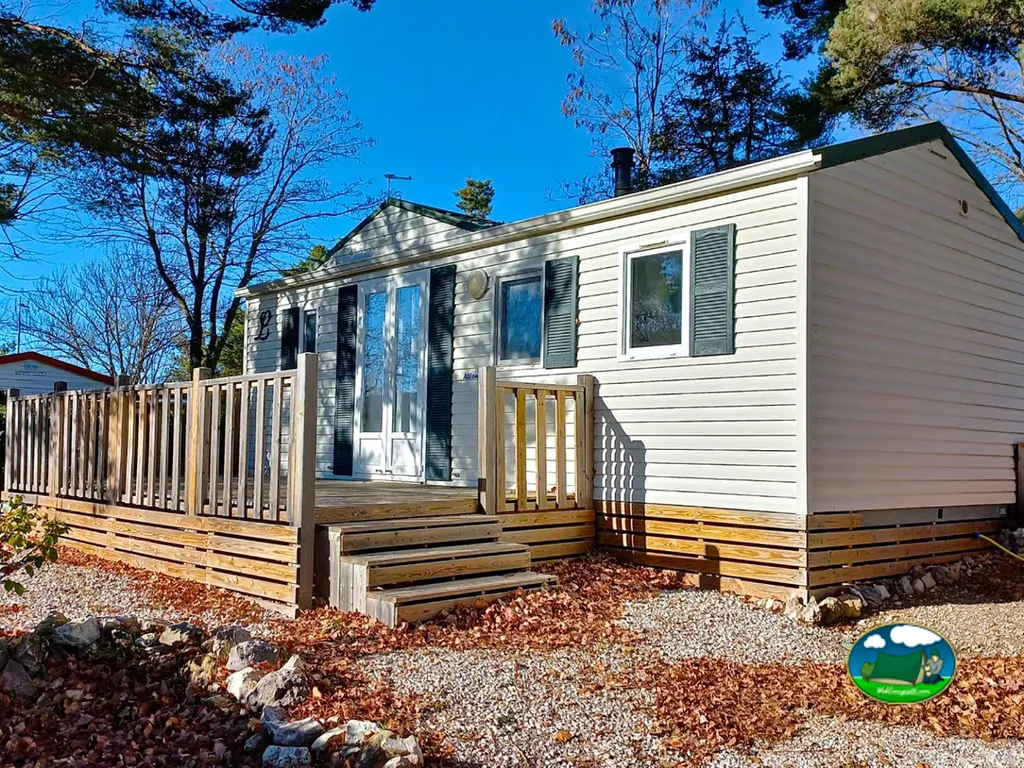 casa móvil con terraza de madera y hojas de otoño en el suelo
