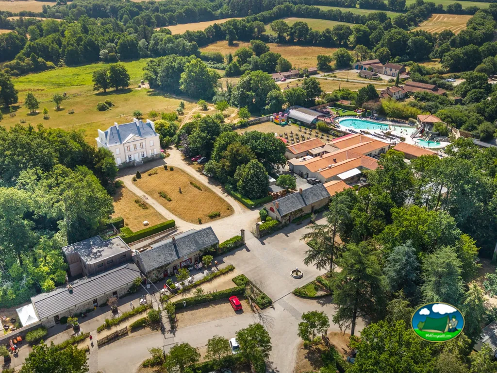 vista aérea del castillo y la piscina del camping rodeados de jardines en Saint-Julien-des-Landes