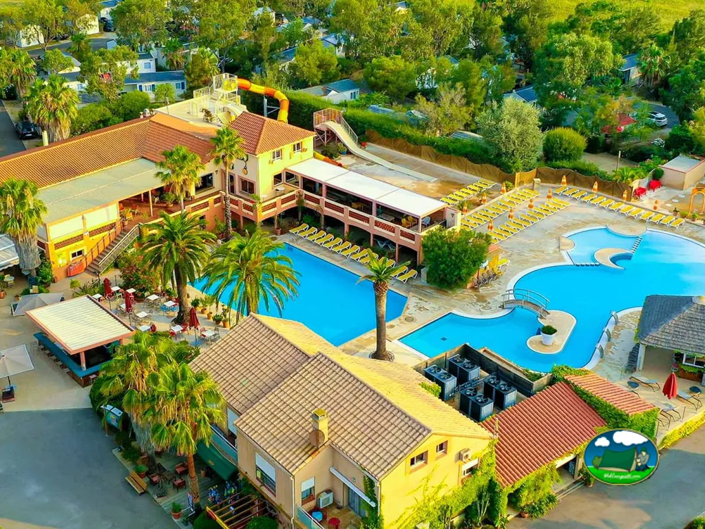 vista aérea de la piscina con tobogán y los edificios del camping en LE BARCARÈS
