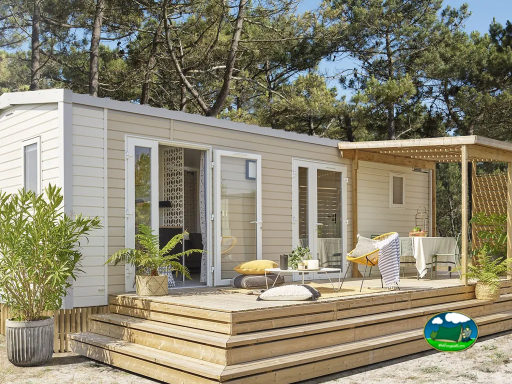 mobil-home con terraza de madera y mobiliario de exterior entre pinos