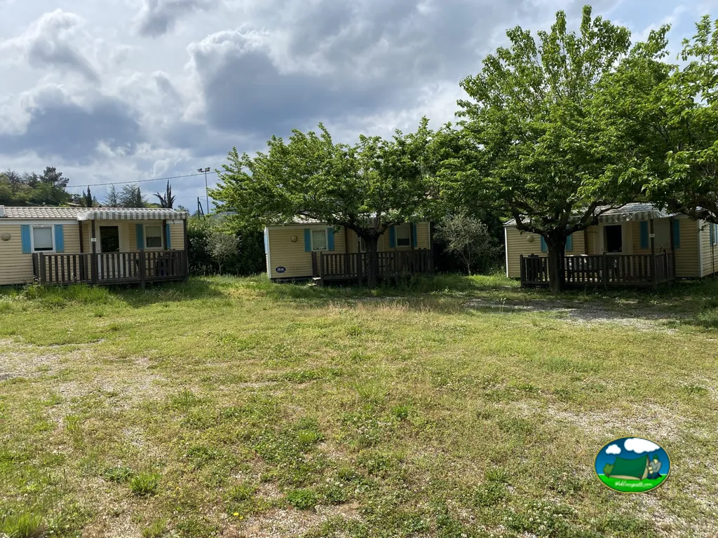 hileras de mobil-homes con terraza entre árboles en un día nublado