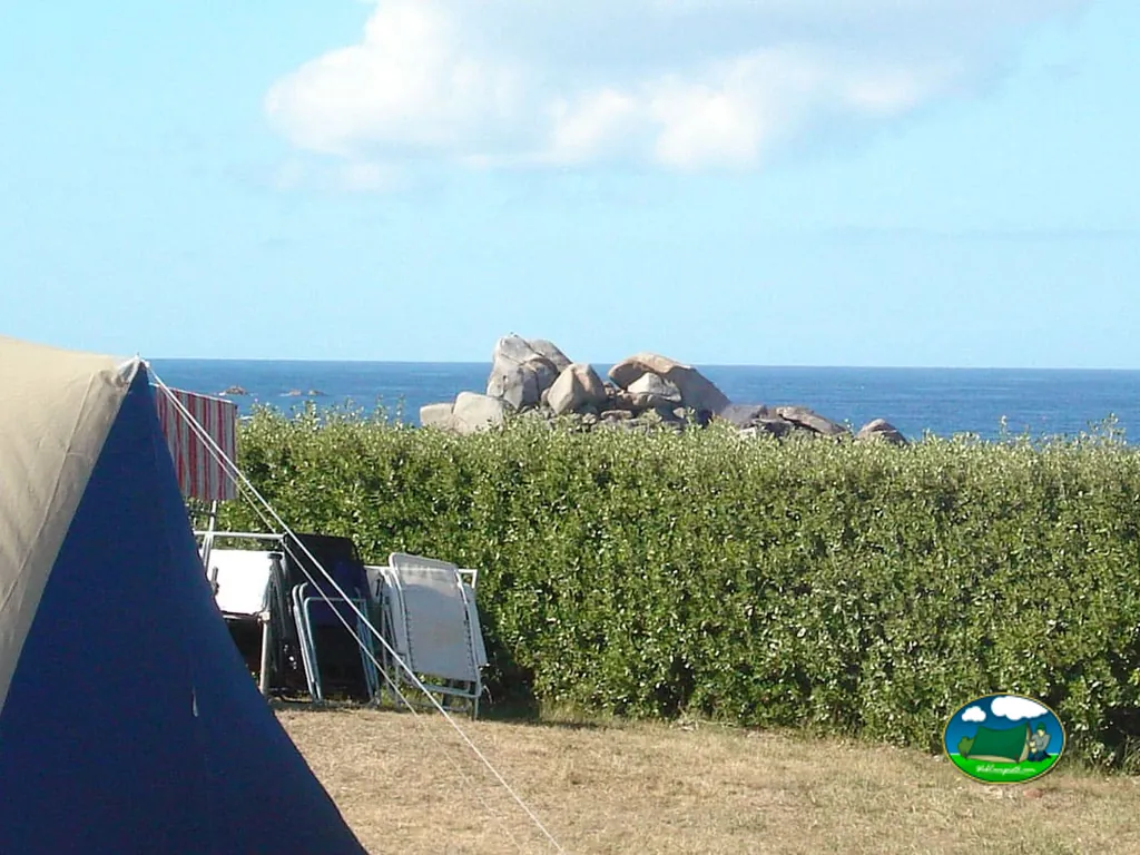 tienda de campaña con vistas al mar y rocas tras un seto en Cléder