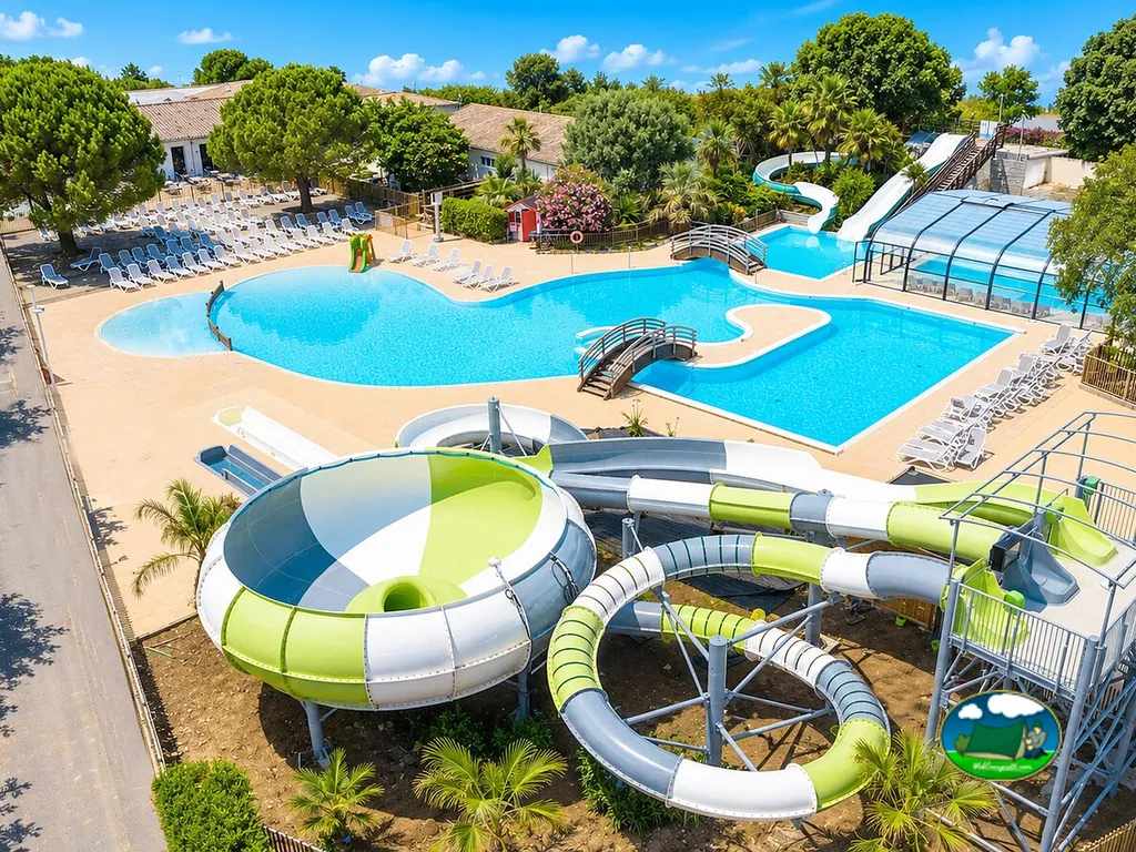 piscina con tobogán de agua y tumbonas bajo palmeras en Saint-Georges-d'Oléron