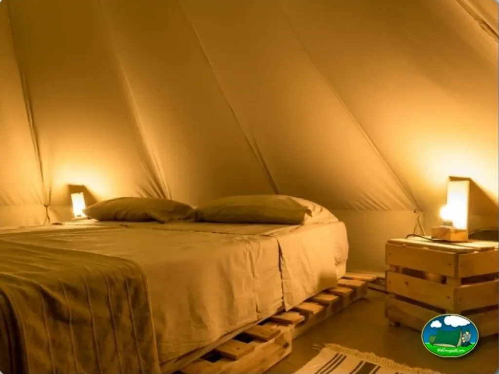 Glamping tipi interior con cama y iluminación del Camping Playa Taray, La Redondela (Huelva)