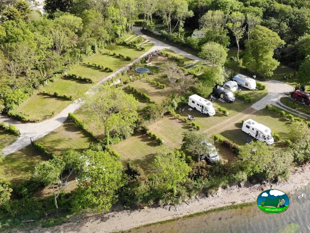 vista aérea de parcelas para autocaravanas entre árboles junto a la orilla