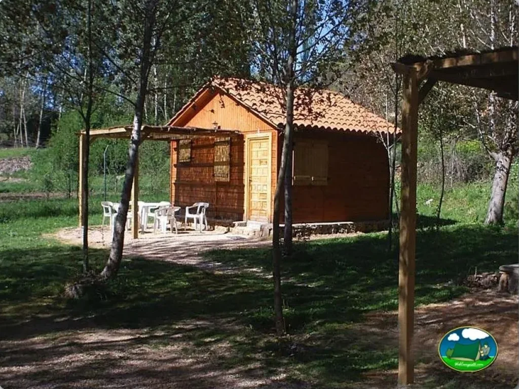 Cabaña de madera en entorno forestal con pérgola del Camping Sierra de Peñascosa, Peñascosa (Albacete)