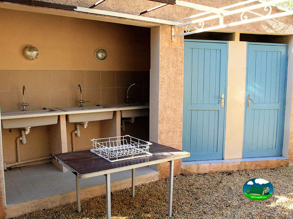 zona de fregaderos exteriores junto a dos puertas azules de aseos en el camping de Cotignac