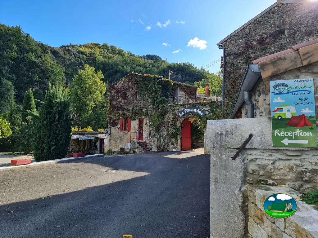 entrada de recepción del camping Le Moulin d'Onclaire en un edificio de piedra con cartel indicador