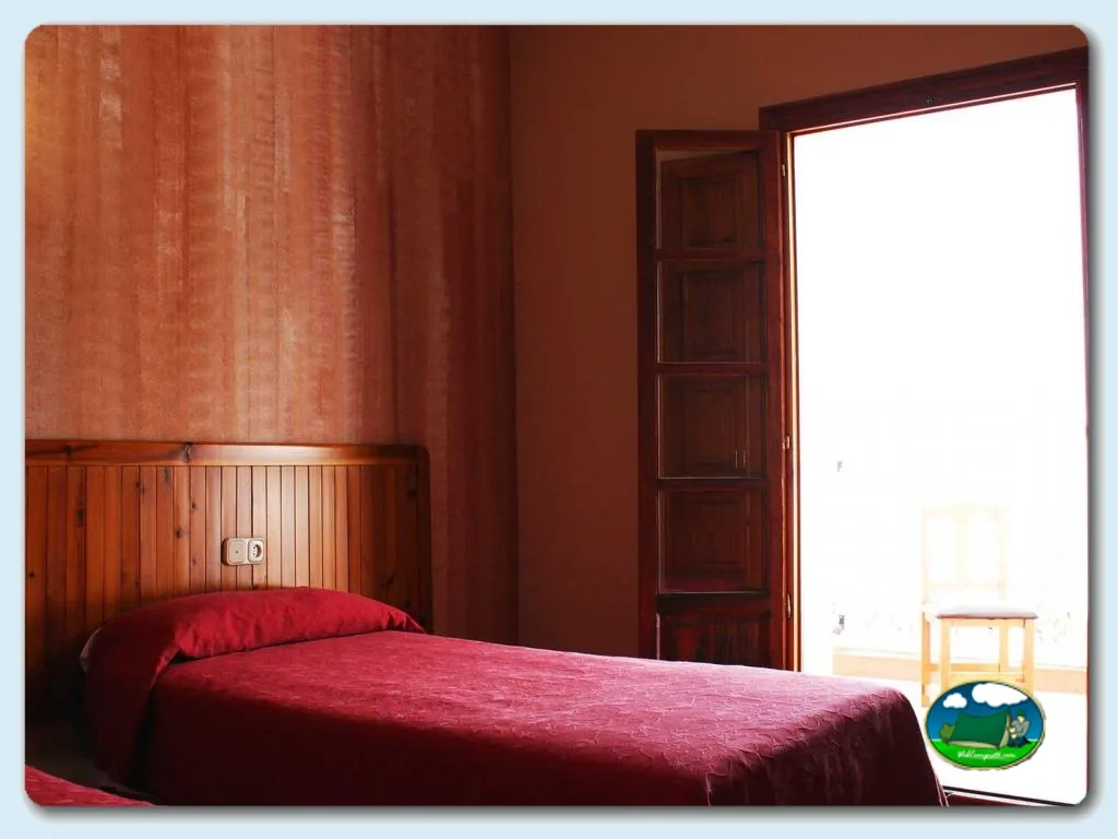 Habitación con cama de matrimonio y paredes rojo tierra del Camping La Rafa, Bullas (Murcia)