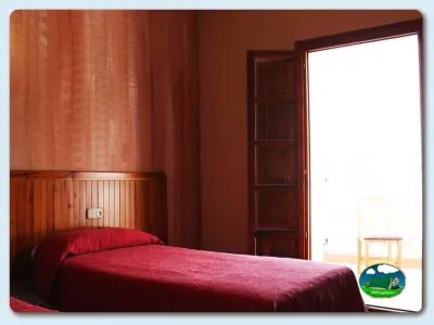 Habitación con cama de matrimonio y paredes rojo tierra del Camping La Rafa, Bullas (Murcia)
