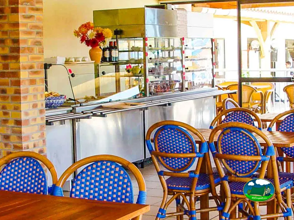 interior del restaurante con sillas de mimbre azul y vitrina de la barra en La Tranche-sur-Mer