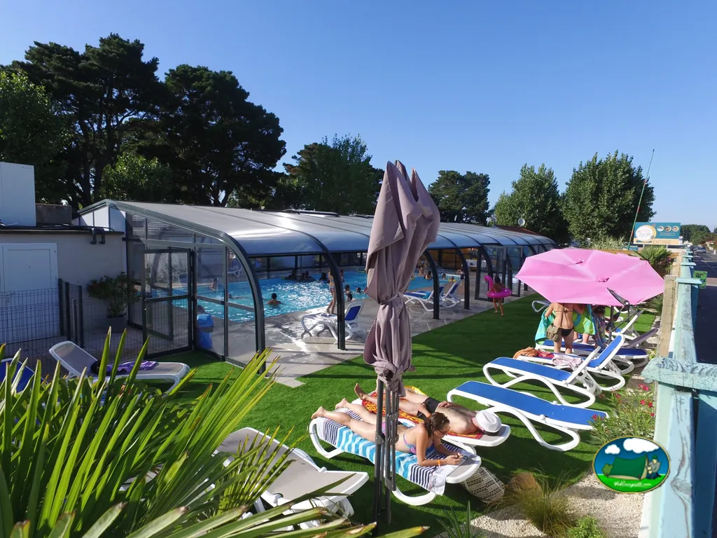 tumbonas junto a la piscina cubierta con parejas tomando el sol bajo sombrillas en Le Fenouiller