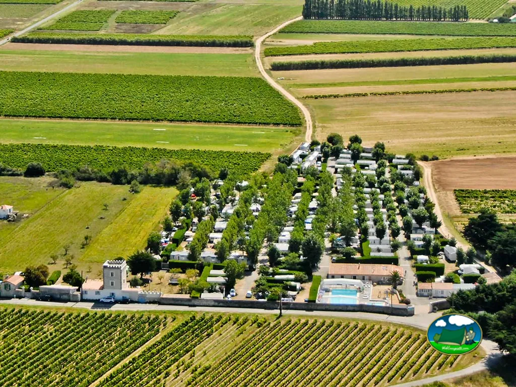 vista aérea del camping entre viñedos con torre histórica y piscina en La Couarde-sur-Mer