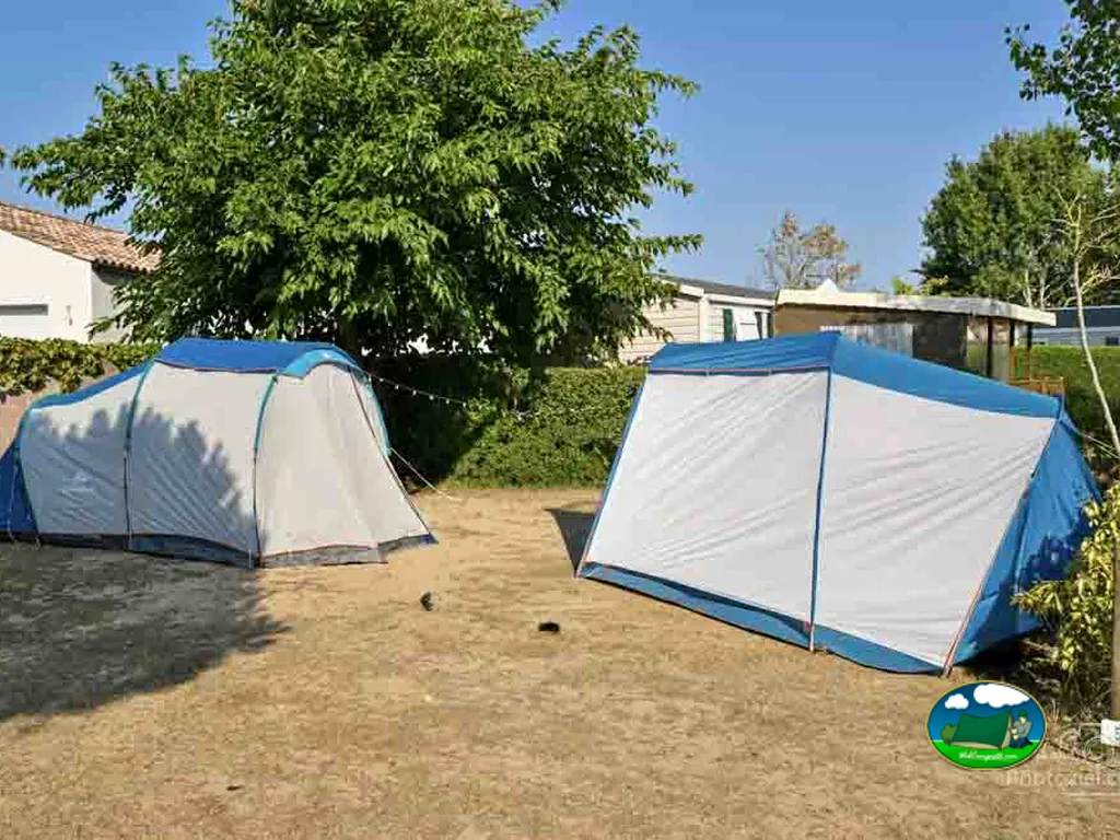 dos tiendas de campaña montadas en una parcela con mobil-homes al fondo