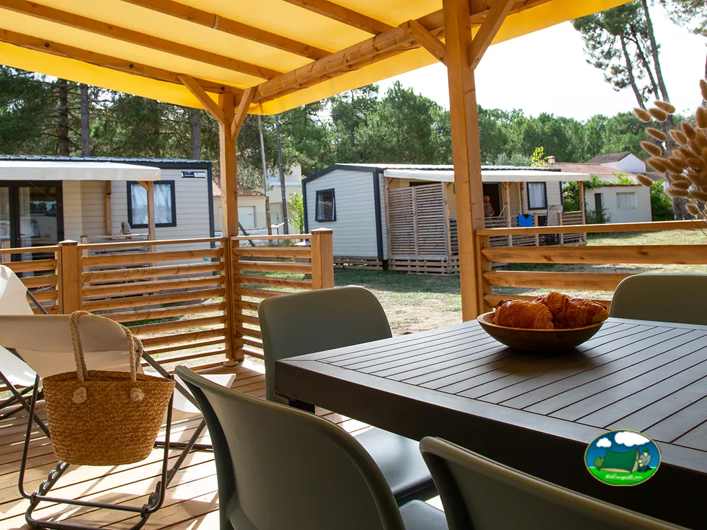 mesa con bol de cruasanes bajo un porche de madera junto a mobil homes en Saint-Jean-de-Monts