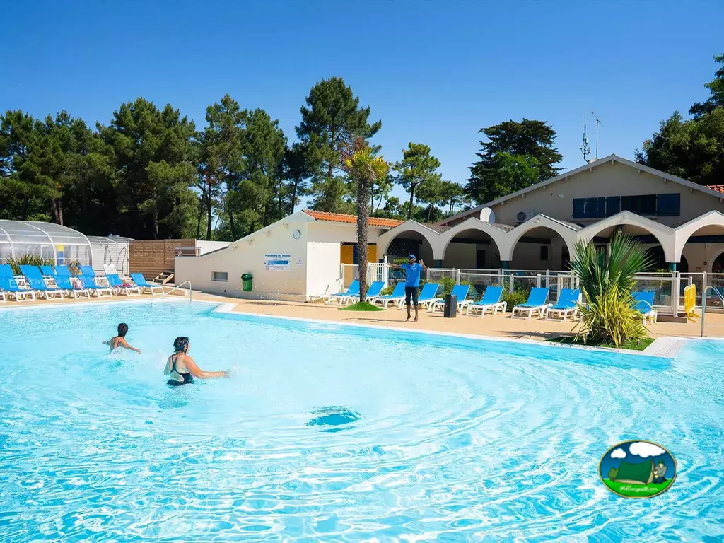 piscina con bañistas y un monitor junto al edificio principal del camping en Saint-Jean-de-Monts