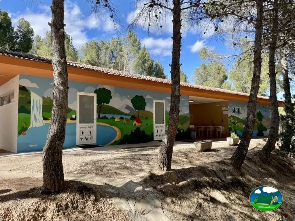 Aseos infantiles con mural temático entre árboles del Camping Lago Resort, Nuévalos (Zaragoza)