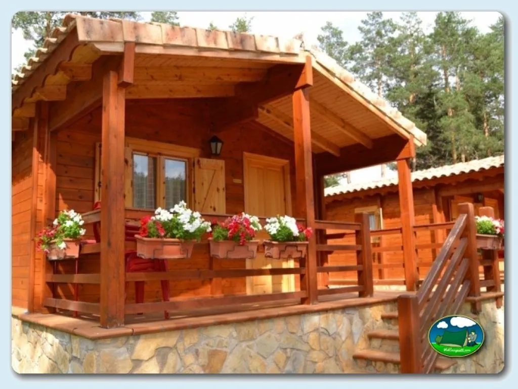 Cabaña de madera con porche y flores del Camping Orea, Orea (Guadalajara)