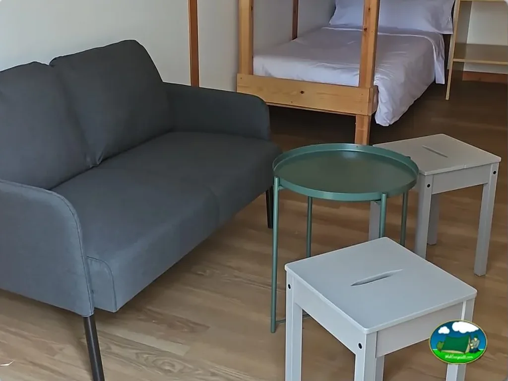 Glamping interior con sofá y cama del Camping Las Cabañas, Martin del Rio (Teruel)
