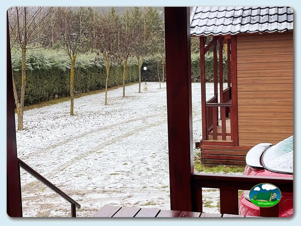 Parcela con cabaña de madera y zona ajardinada del Camping Los Alamos, Alcalá de la Selva (Teruel)