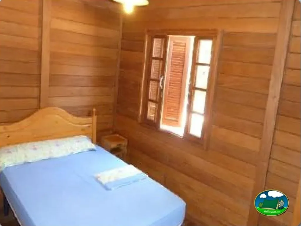 Cabaña de madera interior con cama y entrada del Camping Coelius, Miramar (Valencia)