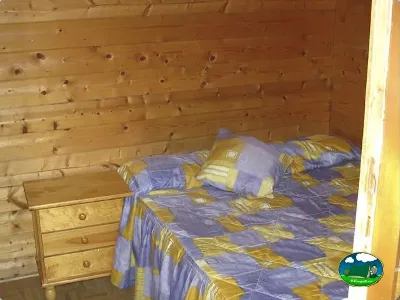 Cabaña interior con cama y mobiliario de madera del Camping L`Alqueria, Gandía (Valencia)