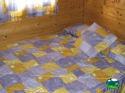 Cabaña interior con cama doble y ropa de cama del Camping L`Alqueria, Gandía (Valencia)