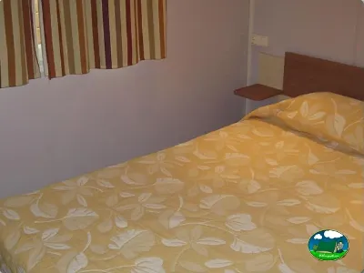 Habitación con cama doble y cortinas del Camping L`Alqueria, Gandía (Valencia)