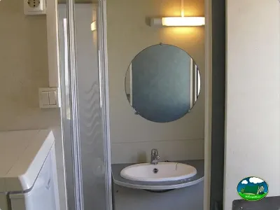 Baño con lavamanos y espejo redondo del Camping L`Alqueria, Gandía (Valencia)