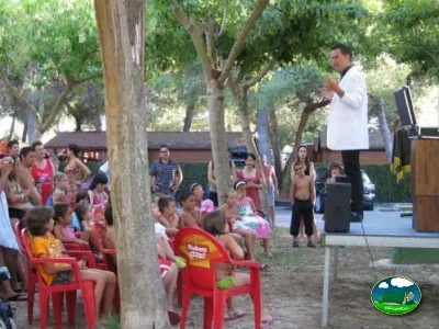 Actividad infantil con animador bajo árboles del Camping L`Alqueria, Gandía (Valencia)