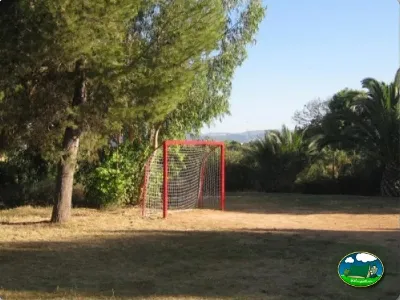 Parque infantil con portería de fútbol entre árboles del Camping L`Alqueria, Gandía (Valencia)