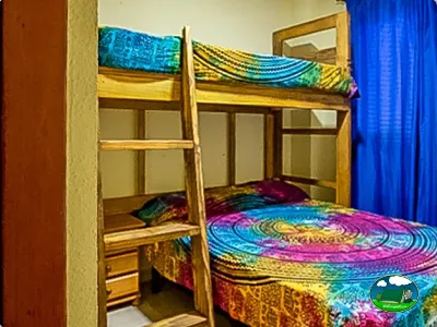 Tienda de acampada con literas de madera y ropa de cama colorida del Camping San Vicente, Xeraco (Valencia)