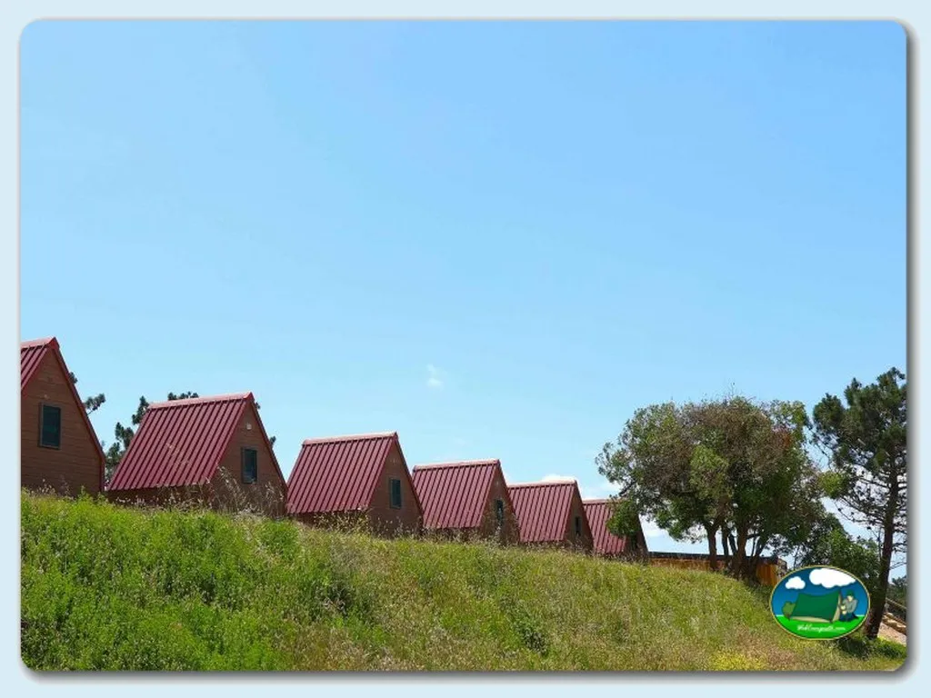 Glamping cabañas con tejado rojo en ladera verde del Camping Ericeira, Ericeira (Lisboa)