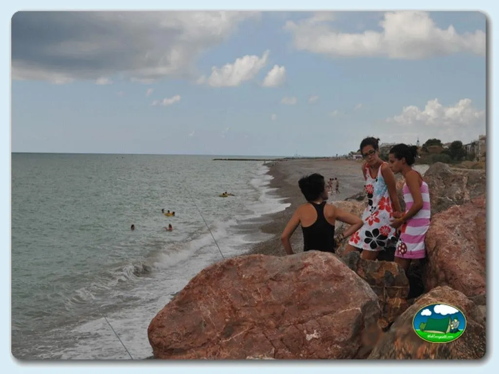 Playa junto al mar con bañistas y acantilados del Camping Costa de Levante, Nules (Castellón)