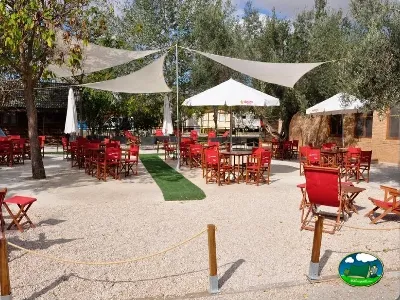 Restaurante bar con sillas rojas y sombrillas blancas del Camping La estanca, Alcañiz (Teruel)