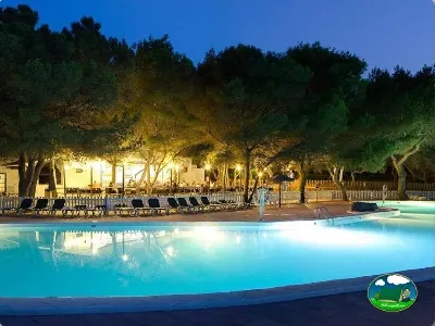 Piscina iluminada atardecer con zona de estar del Camping Son Bou, Alaior (Menorca)