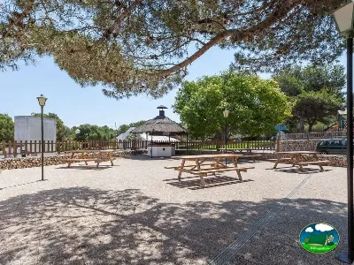 Área de picnic con mesas de madera y zona infantil del Camping Son Bou, Alaior (Menorca)