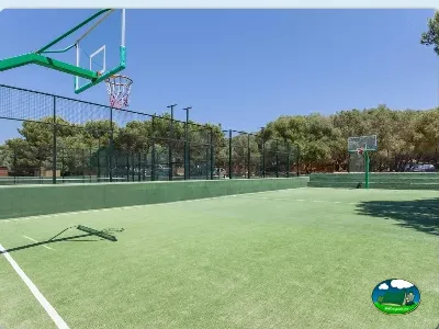 Cancha de baloncesto y pádel con entorno arbolado del Camping Son Bou, Alaior (Menorca)