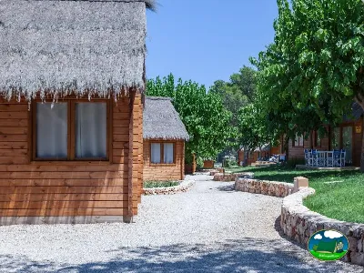 Cabaña con techo de paja y entorno arbolado del Camping Son Bou, Alaior (Menorca)