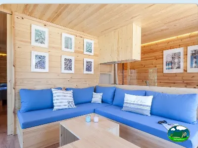 Bungalow interior con sofá azul y techo de madera del Camping Son Bou, Alaior (Menorca)