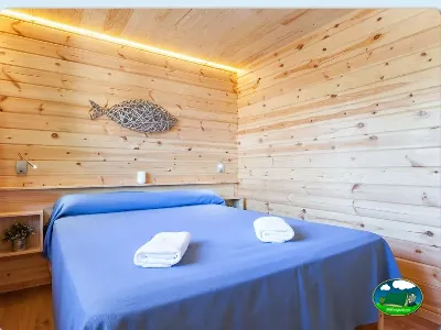 Cabaña de madera con cama doble y iluminación cálida del Camping Son Bou, Alaior (Menorca)