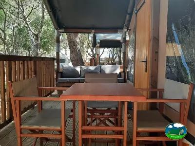 Glamping con terraza y zona de estar entre árboles del Camping Son Bou, Alaior (Menorca)