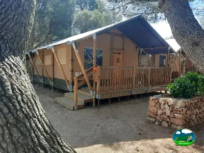Glamping tienda de acampada con terraza de madera entre árboles del Camping Son Bou, Alaior (Menorca)