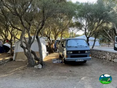 Parcela con tienda de acampada y autocaravana bajo árboles del Camping Son Bou, Alaior (Menorca)
