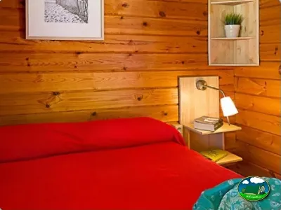 Cabaña interior con cama doble y paredes de madera del Camping Son Bou, Alaior (Menorca)